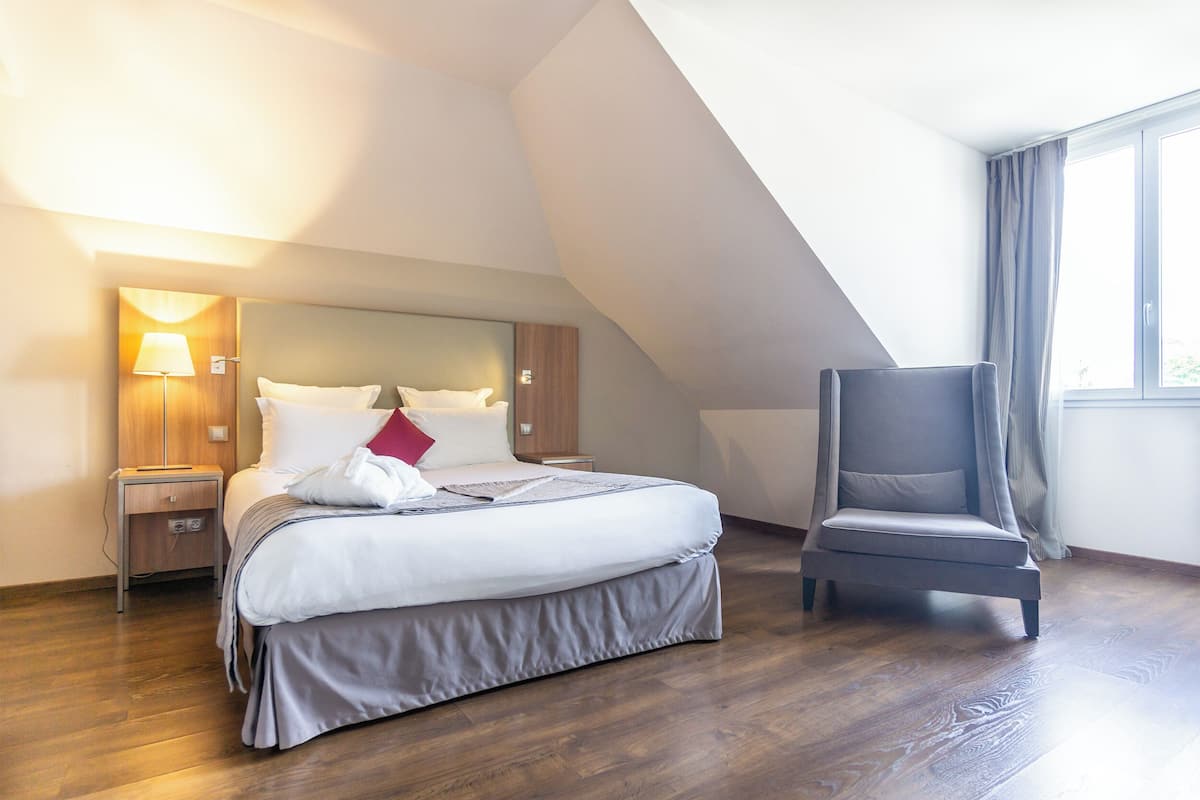 Une chambre d’hôtel moderne avec un grand lit, une table de chevet, une chaise et une fenêtre avec des rideaux.