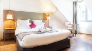 Ein modernes Hotelzimmer mit einem großen Bett, einem Nachttisch, einem kleinen Tisch und einer Lampe.
