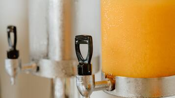 A beverage dispenser with a clear glass container filled with orange juice.