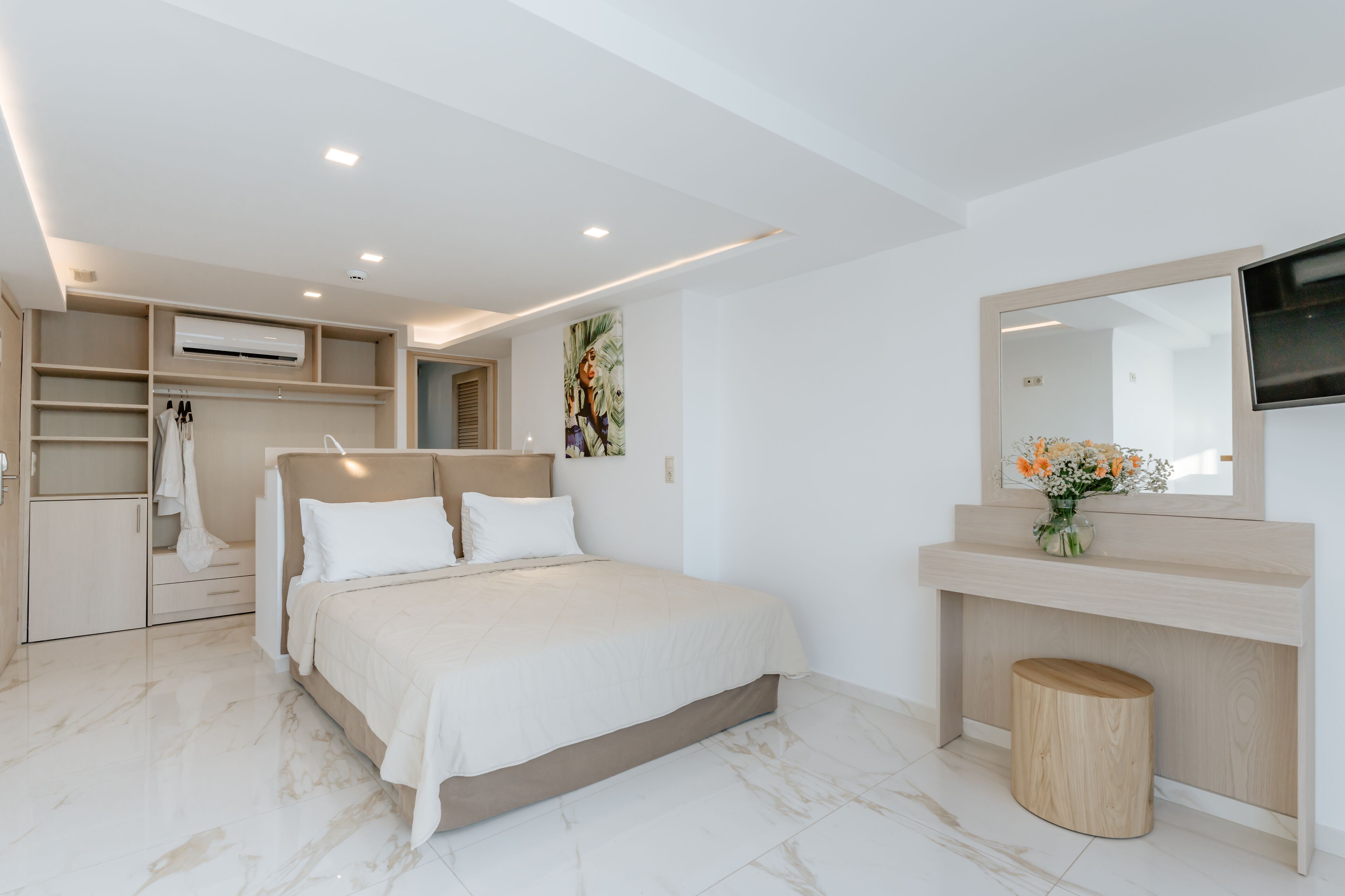 A modern bedroom with a bed, built-in wardrobe, vanity, and a TV.