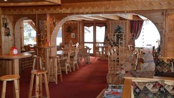 Cozy cabin-style interior with a central seating area, fireplace, and large windows offering scenic views.