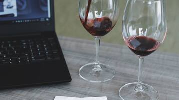 Un ordinateur portable et deux verres à vin sont posés sur une table, à côté d’une feuille de papier.
