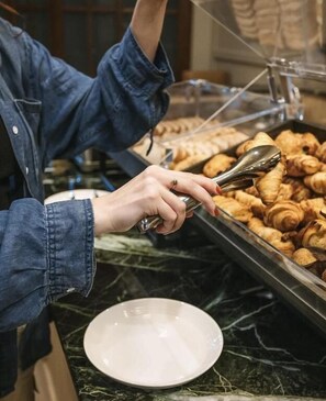 A person serving pastries from a glass container.