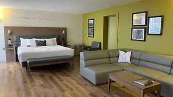 Una habitación de hotel con una cama, un sofá, una mesita de centro y cuadros en la pared.