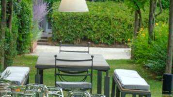 An outdoor dining area with a table set for a meal, including a bottle of wine, glasses, and a pitcher of orange juice.