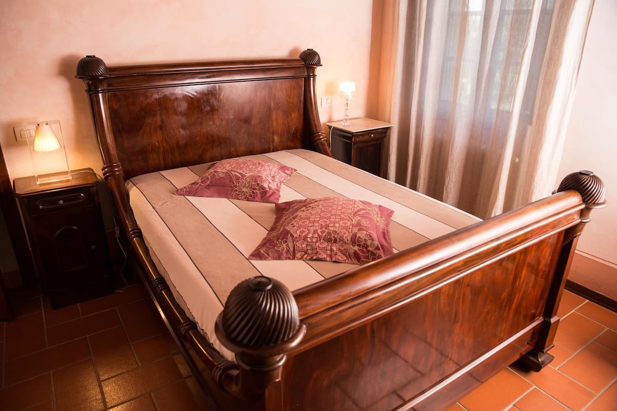 A wooden bed with a headboard, two bedside tables, and a window with curtains.