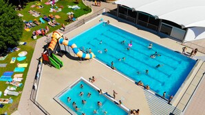 Una piscina con tobogán, rodeada de tumbonas y sombrillas.