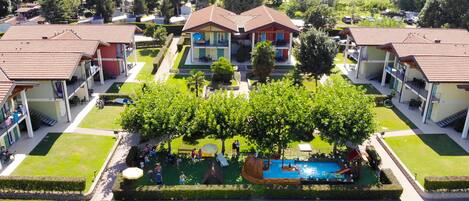Un conjunto residencial con varias casas, una piscina y un jardín bien cuidado.