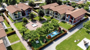 Un barrio residencial con varias casas de dos pisos, una piscina y un césped bien cuidado.