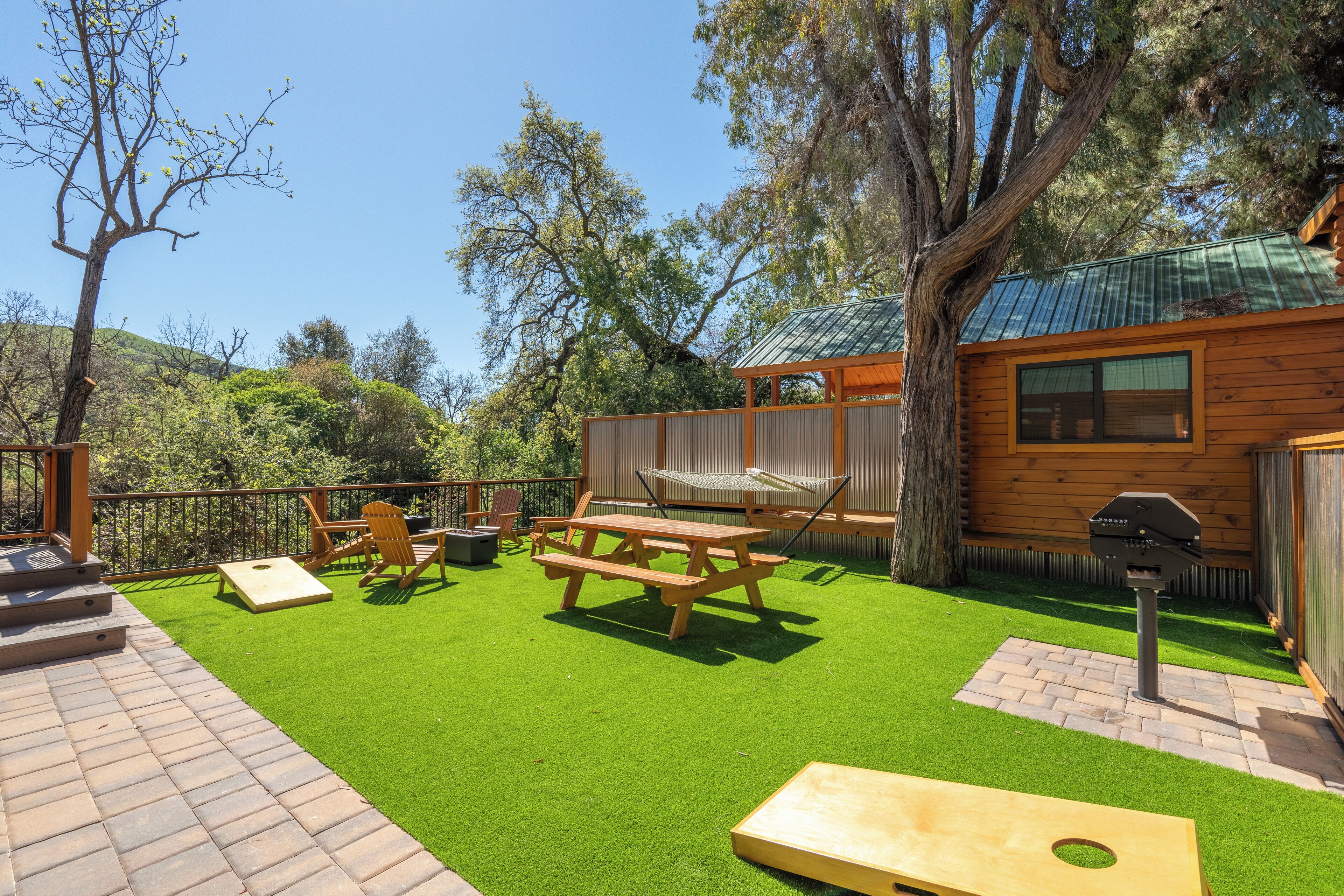 Un jardin avec une terrasse en bois, une table de pique-nique et un hamac.