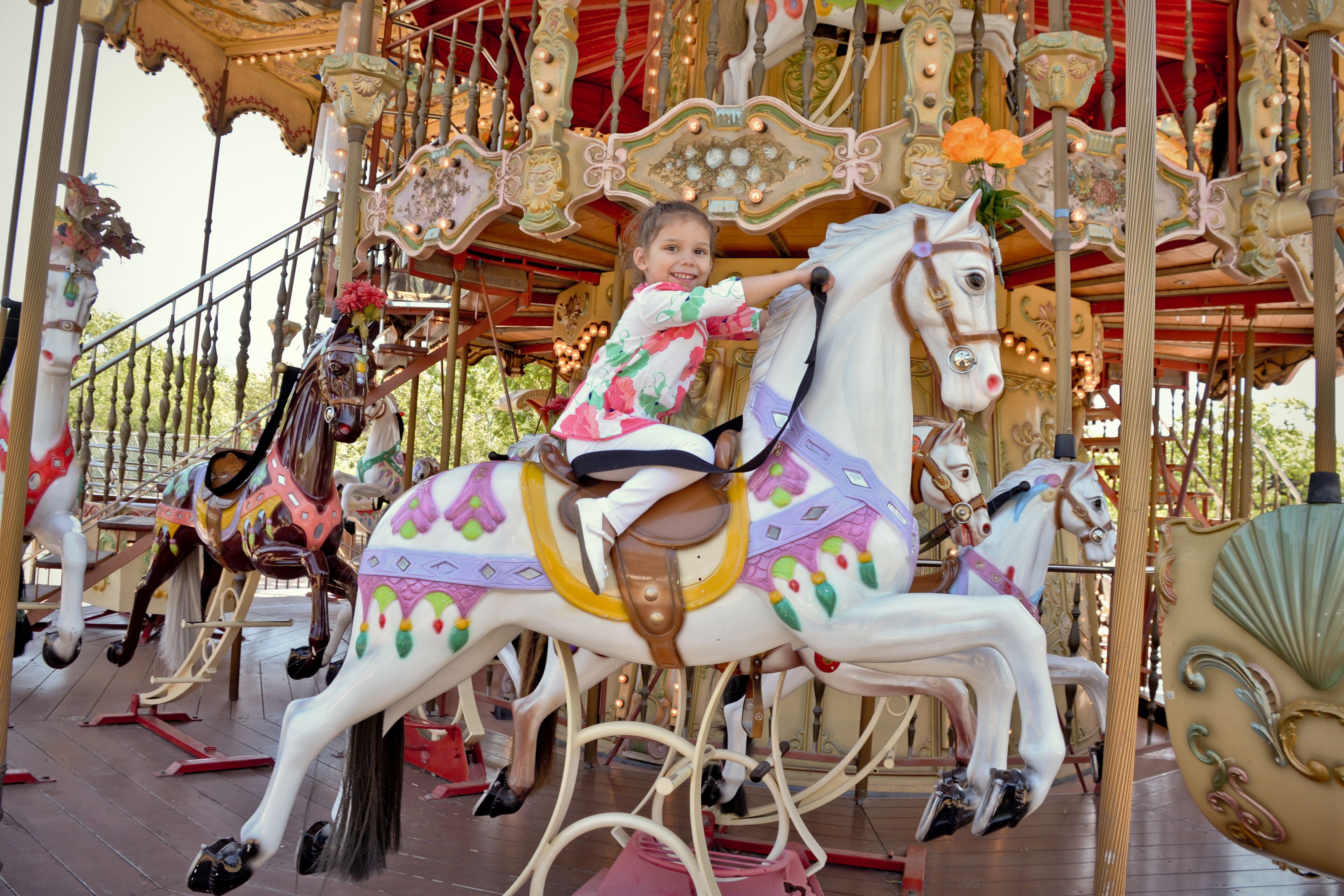 A carousel with ornate decorations and a child riding a horse.