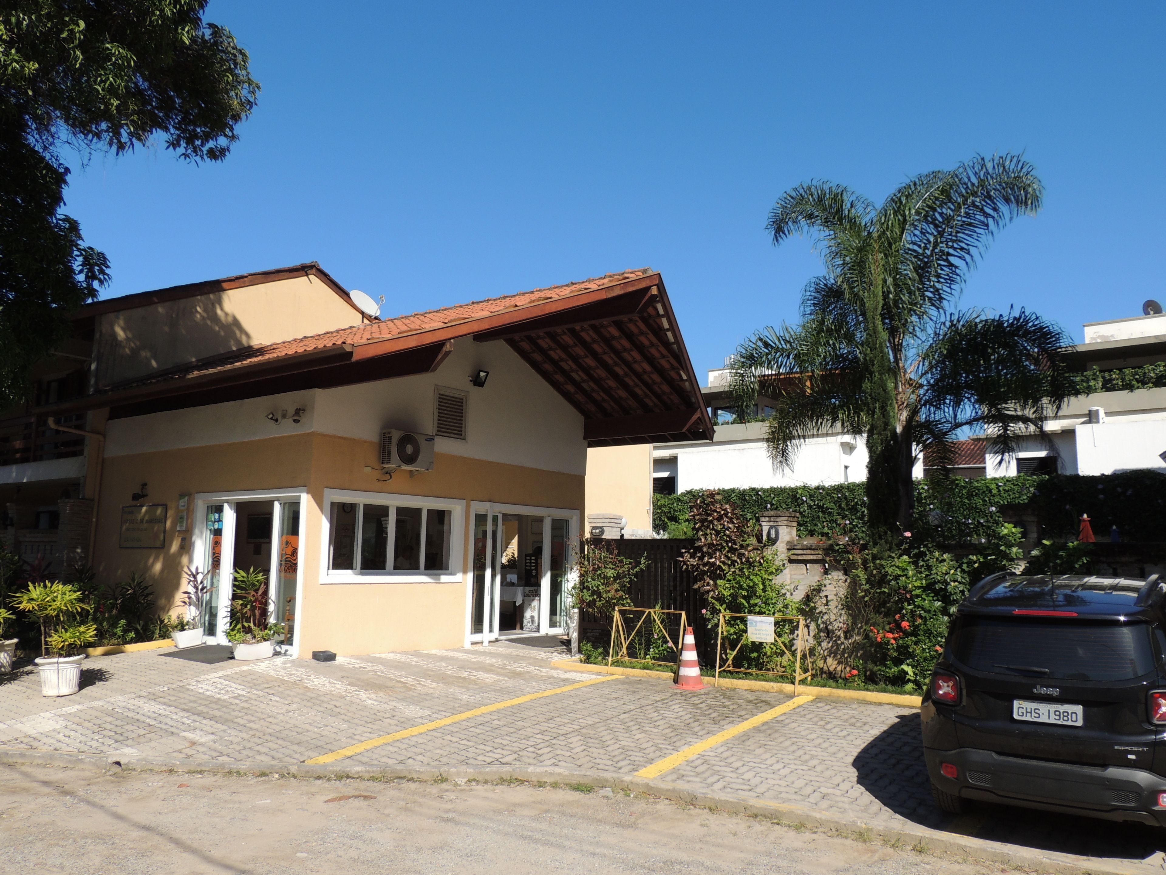 A building with a tiled roof, a paved entrance, and a parked car.
