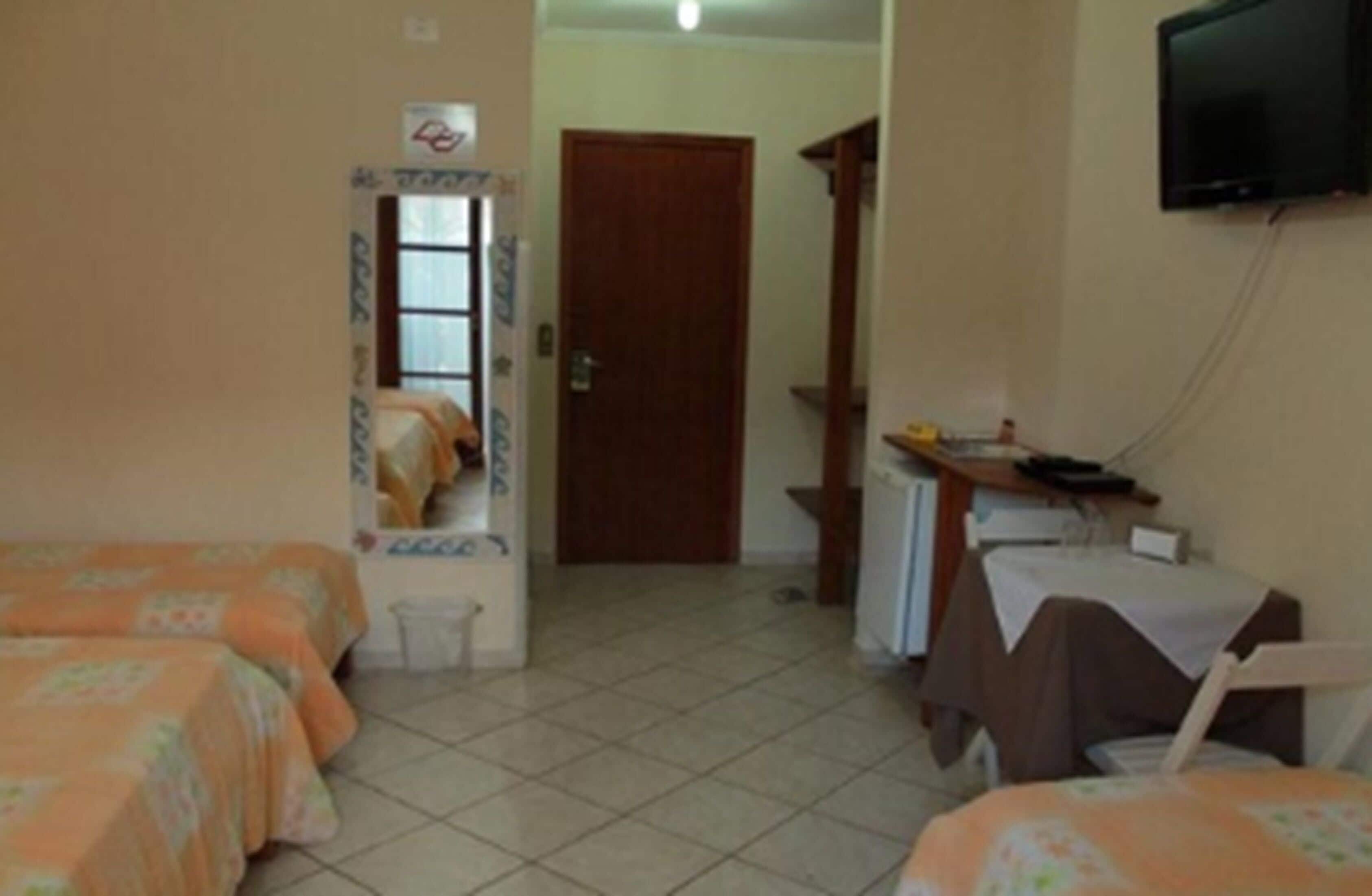 Una habitación de hotel con dos camas, un televisor, un escritorio y una puerta que da a otra habitación.
