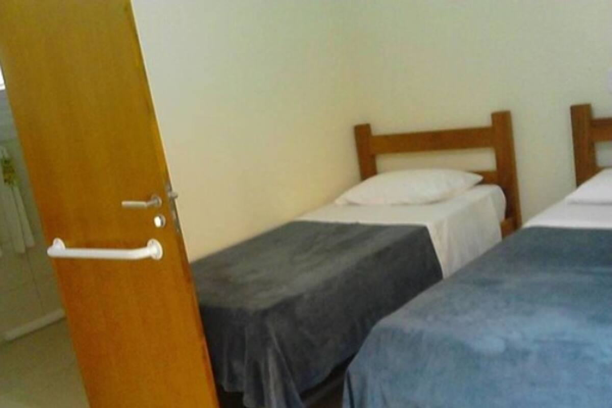 A room with two single beds, wooden headboards, and a door with a white handle.