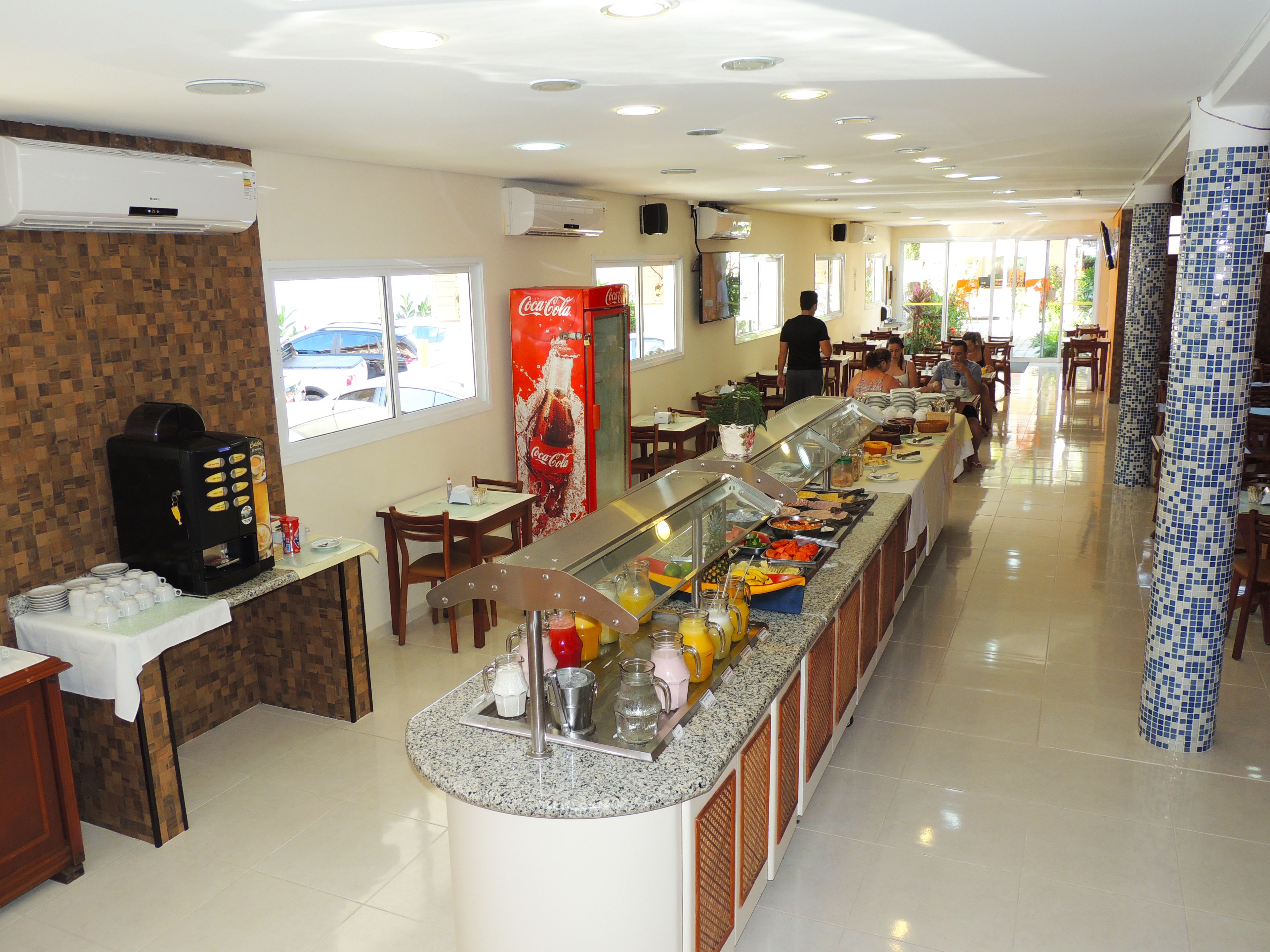 A buffet area with a coffee machine, a Coca-Cola refrigerator, and a variety of food items.