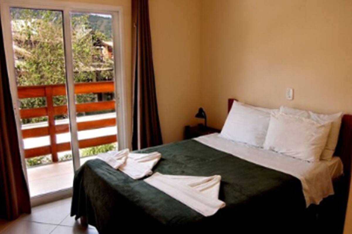 A bedroom with a bed, a nightstand, and a view through a sliding door to an outdoor area.