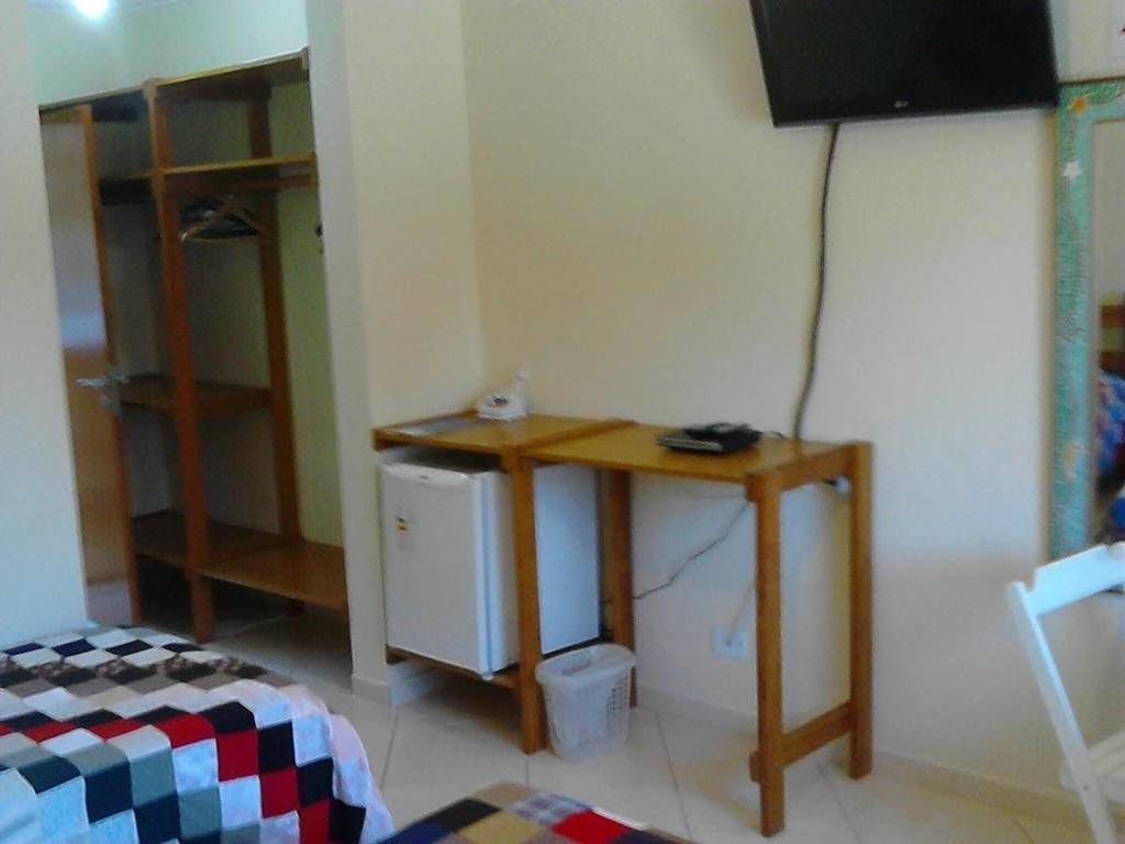 A room with a bed, a desk with a computer, a TV, and a wardrobe.