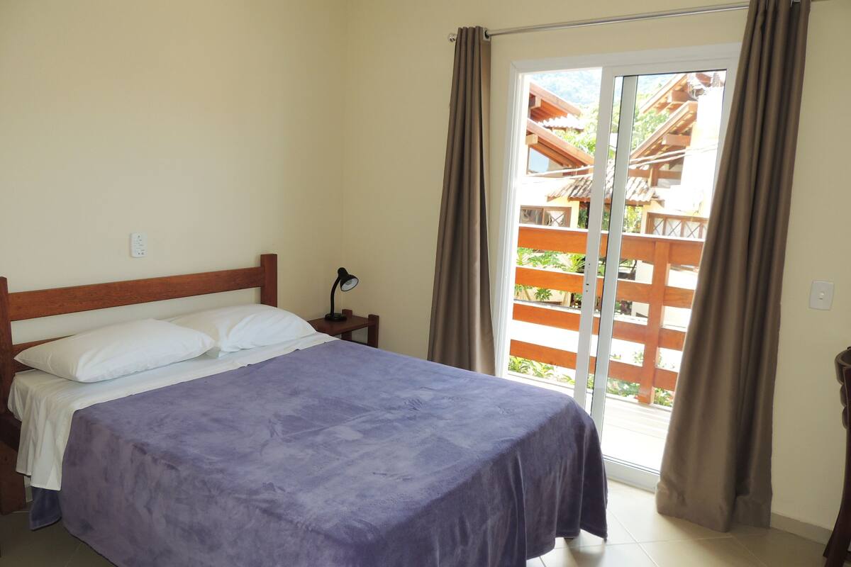 A bedroom with a bed, a nightstand, and a window with curtains.