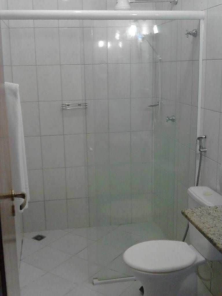 A bathroom with a glass-enclosed shower, a toilet, and a sink with a countertop.