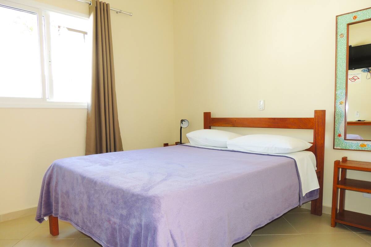 A single bed with a wooden headboard, a bedside table, and a mirror on the wall.
