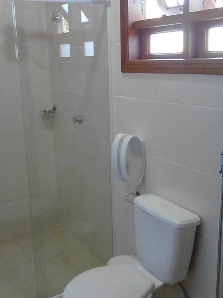 A bathroom with a glass-enclosed shower, a toilet, and a mirror above the sink.
