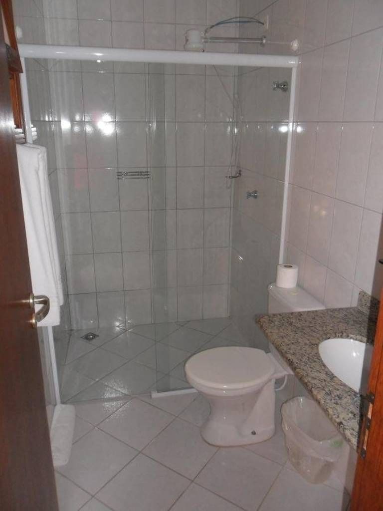 A bathroom with a glass-enclosed shower, a toilet, and a sink.