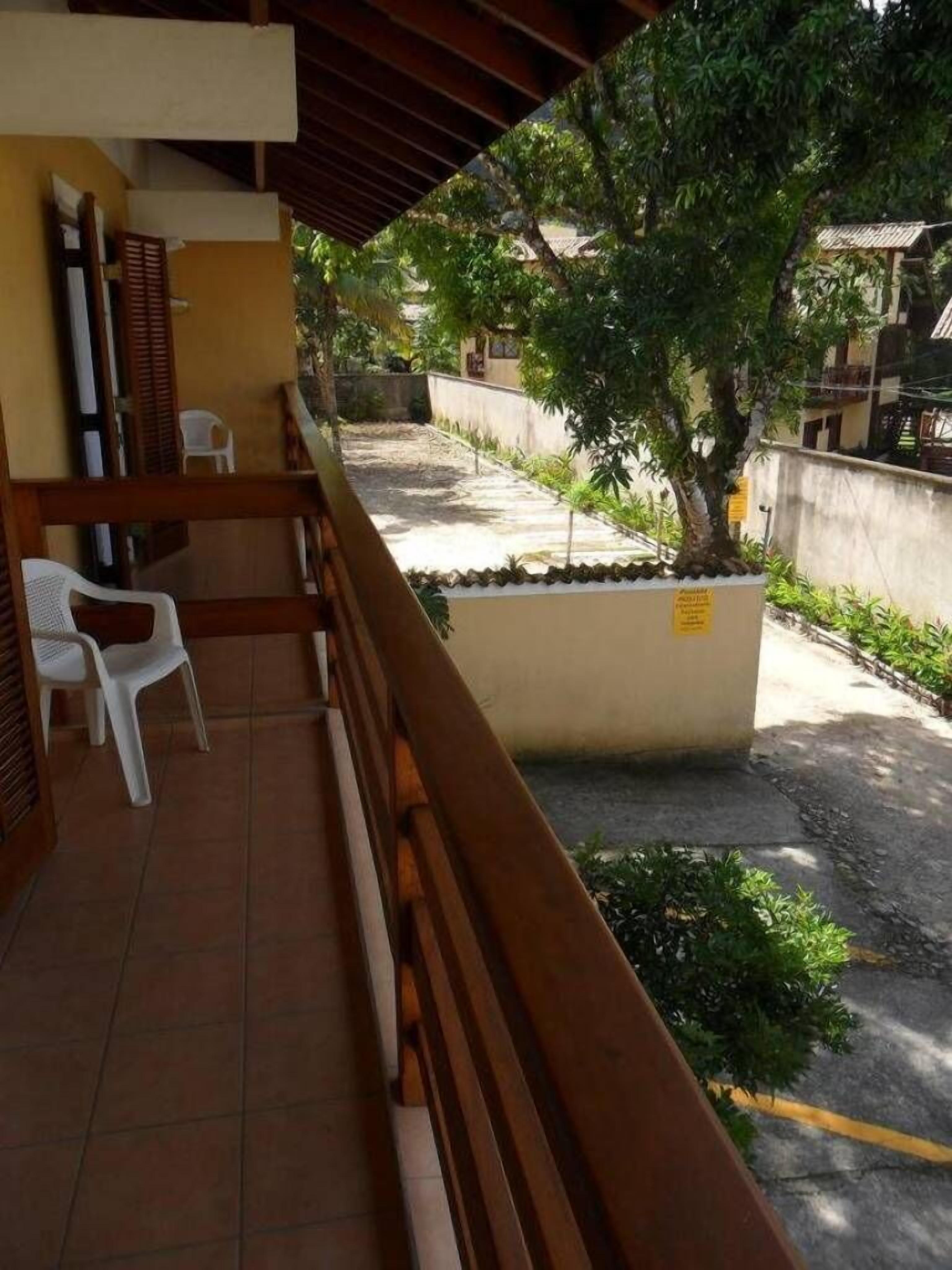 A balcony with a wooden railing, a white plastic chair, and a potted plant.