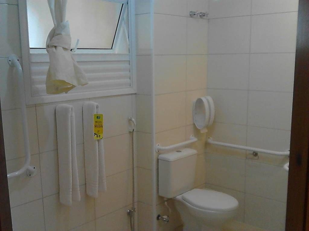 Un baño con inodoro, ducha y perchero para toallas.