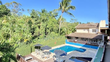 Una piscina al aire libre, sombrillas, sillones reclinables de piscina