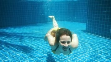 Una piscina al aire libre, sombrillas, sillones reclinables de piscina