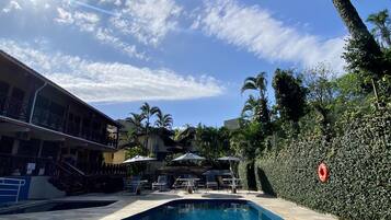 Una piscina al aire libre, sombrillas, tumbonas
