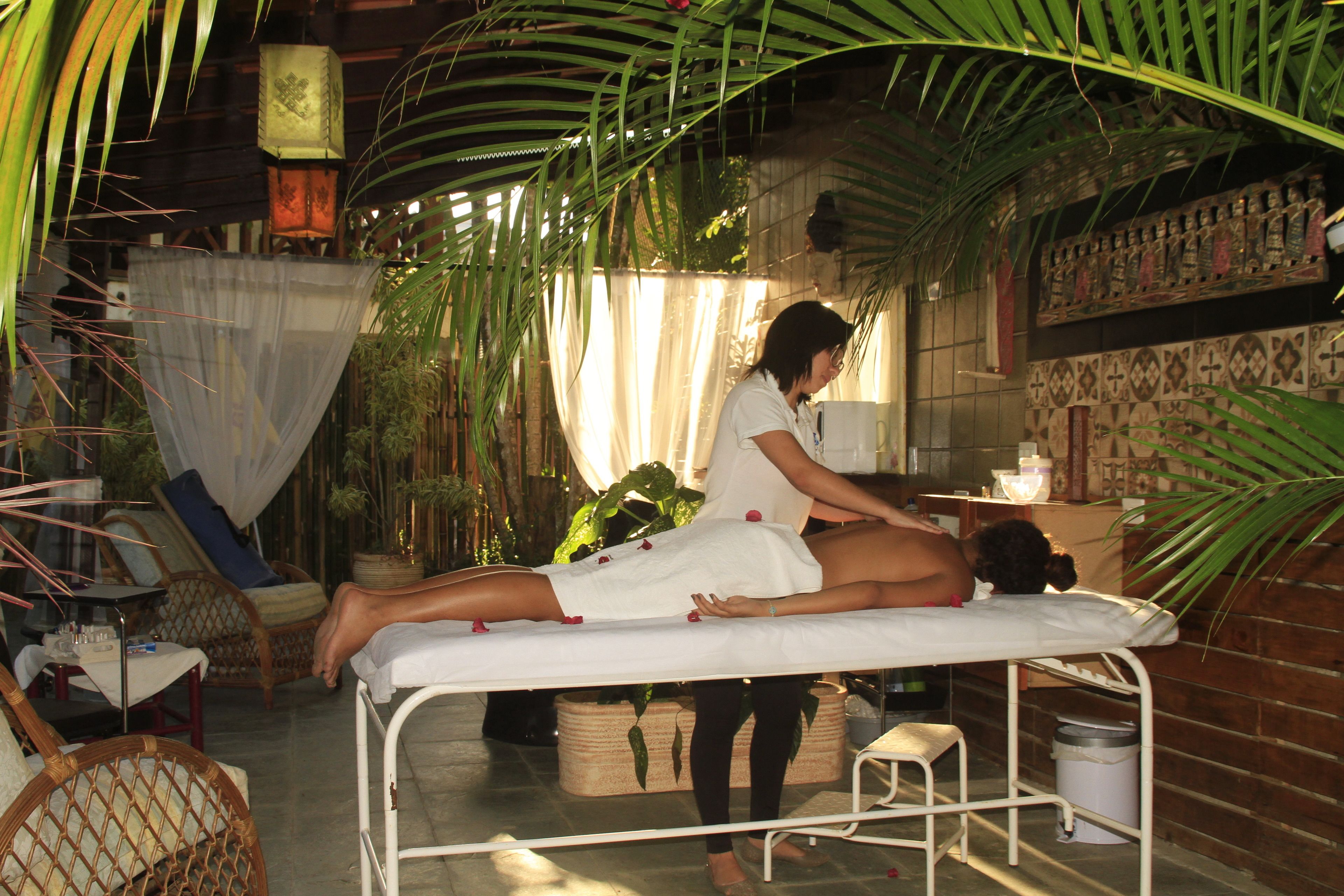 Une salle de massage équipée d’un lit, d’un petit tabouret et d’une chaise en osier.