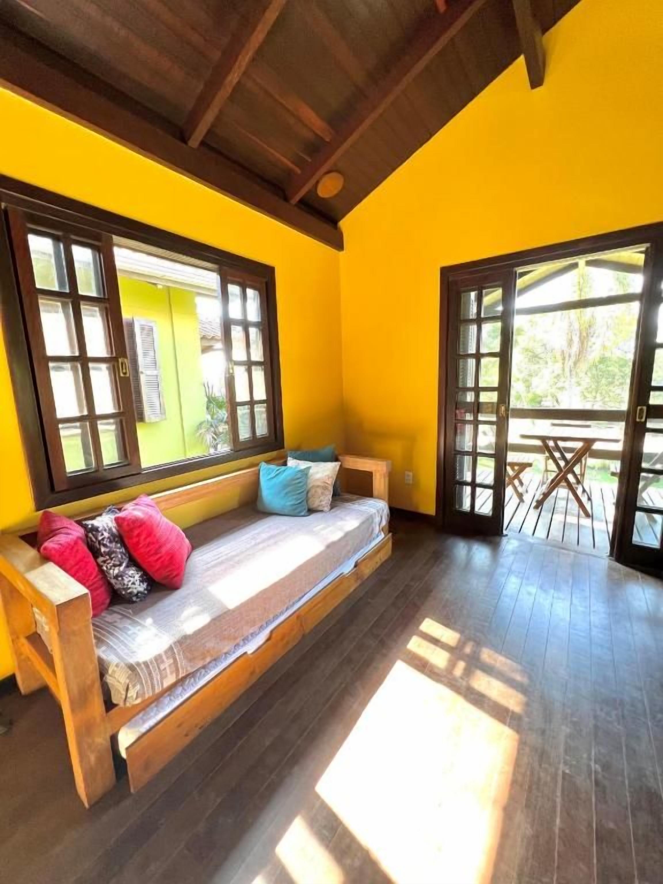 A room with a wooden bench, large windows, and a view of the outdoors.