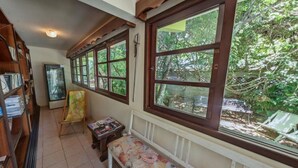 A narrow hallway with wooden bookshelves, a small table, and a chair. - Pousada Mariane (Bombinhas)