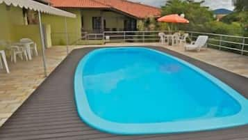 Una piscina al aire libre, sombrillas, sillones reclinables de piscina