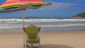 A beach scene with a person in a wheelchair under a colorful umbrella. - Pousada Mariane (Bombinhas)