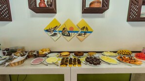 A buffet table with various food items and decorative wall art. - Pousada Mariane (Bombinhas)