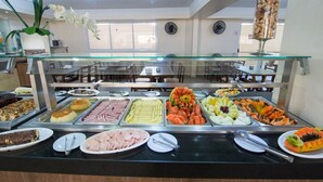 A buffet with various food items and a glass display case. - Hotel Guarumar (Guarujá)