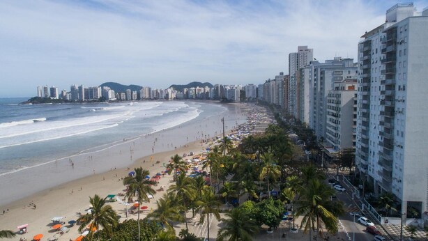 A beach with a row of high-rise buildings along the shore. - Hotel Guarumar (Guarujá)