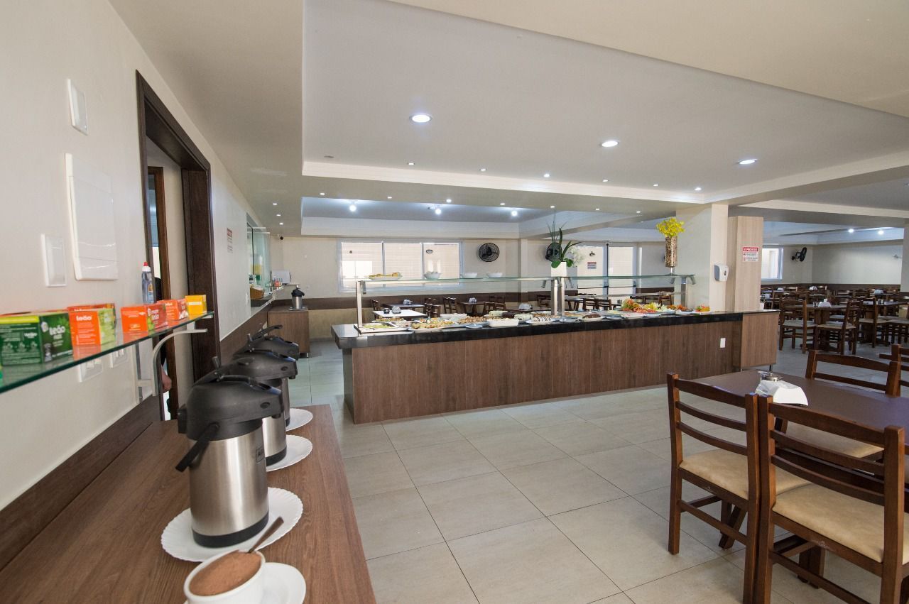 A buffet area with a central serving station, multiple seating tables, and a variety of food items displayed.