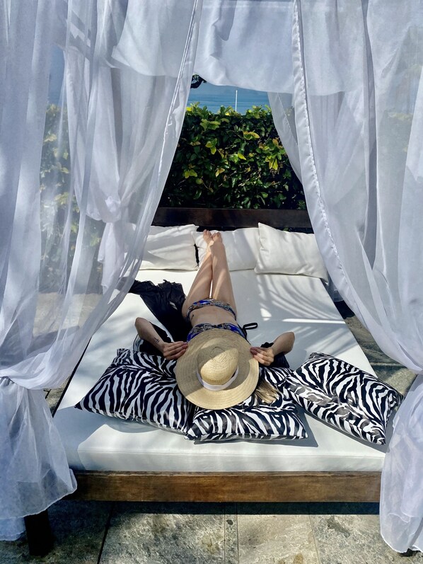 Una piscina al aire libre, sombrillas, sillones reclinables de piscina