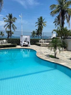 Una piscina al aire libre, sombrillas, sillones reclinables de piscina