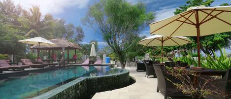 Alberca al aire libre, sombrillas en la alberca y camastros