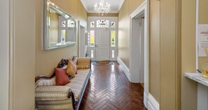 A hallway with a herringbone floor, a sofa with patterned upholstery, and a chandelier. - Clydesdale Manor (Sandy Bay)