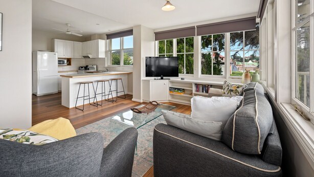 A modern living room with a grey sofa, a glass coffee table, and a TV on a stand. - Clydesdale Manor (Sandy Bay)