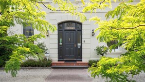 A building with a dark entrance door, a brick pathway leading to it, and surrounding greenery. - Clydesdale Manor (Sandy Bay)