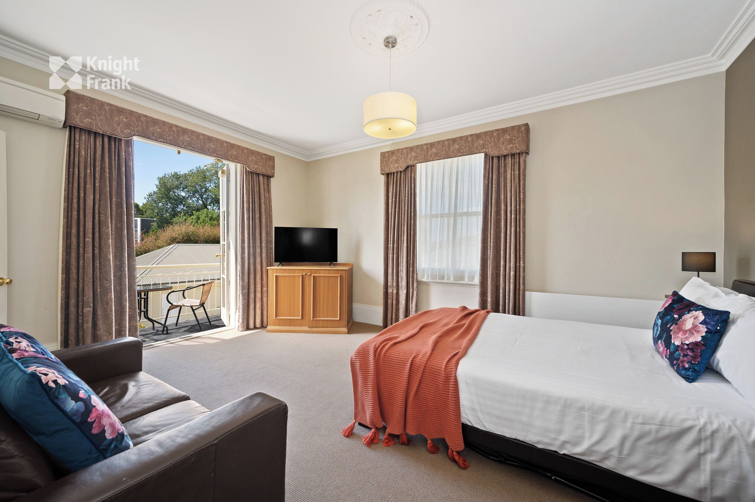 A hotel room with a bed, a TV, a sofa, and a view of the outdoors.