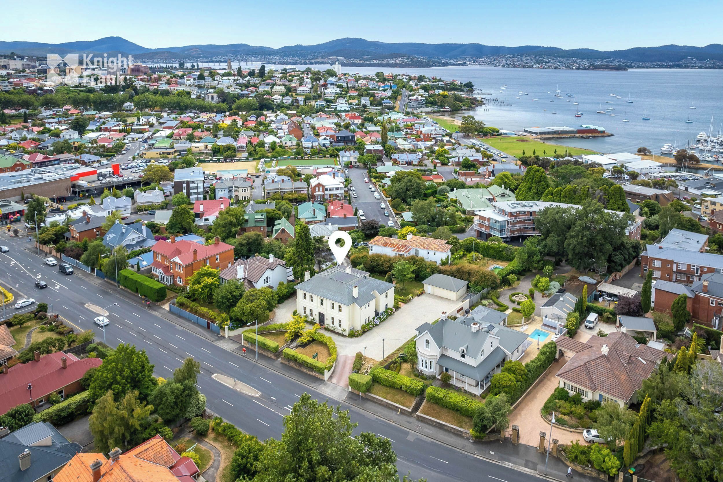 A residential area with houses, a road, and a marina with boats.