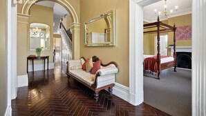A spacious hallway with a herringbone wood floor, a vintage sofa, and a large mirror. - Clydesdale Manor (Sandy Bay)