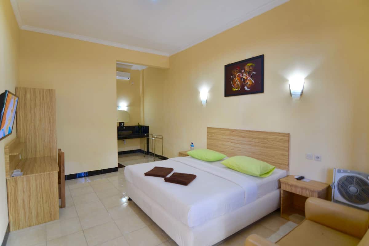 A hotel room with a bed, a desk, a mirror, and a television.
